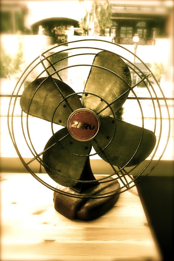 electric fan blowing air in a bedroom with green plant nearby, summer night