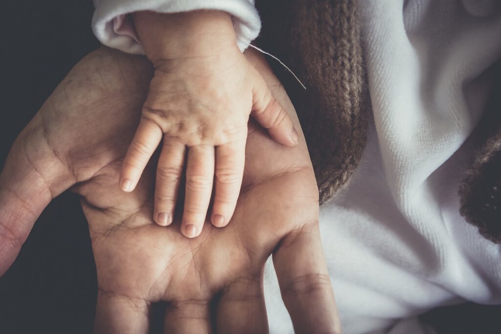 adult child handing handmade desiccant sachet to smiling elderly parent at home