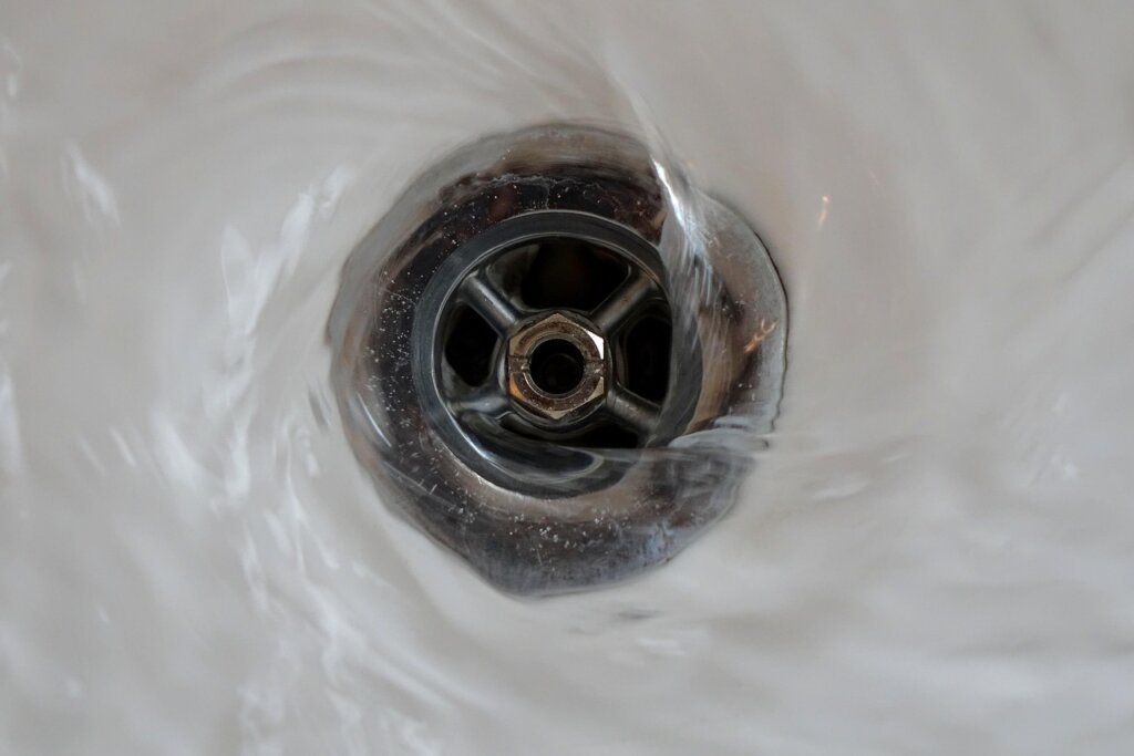 person pouring baking soda into sink drain