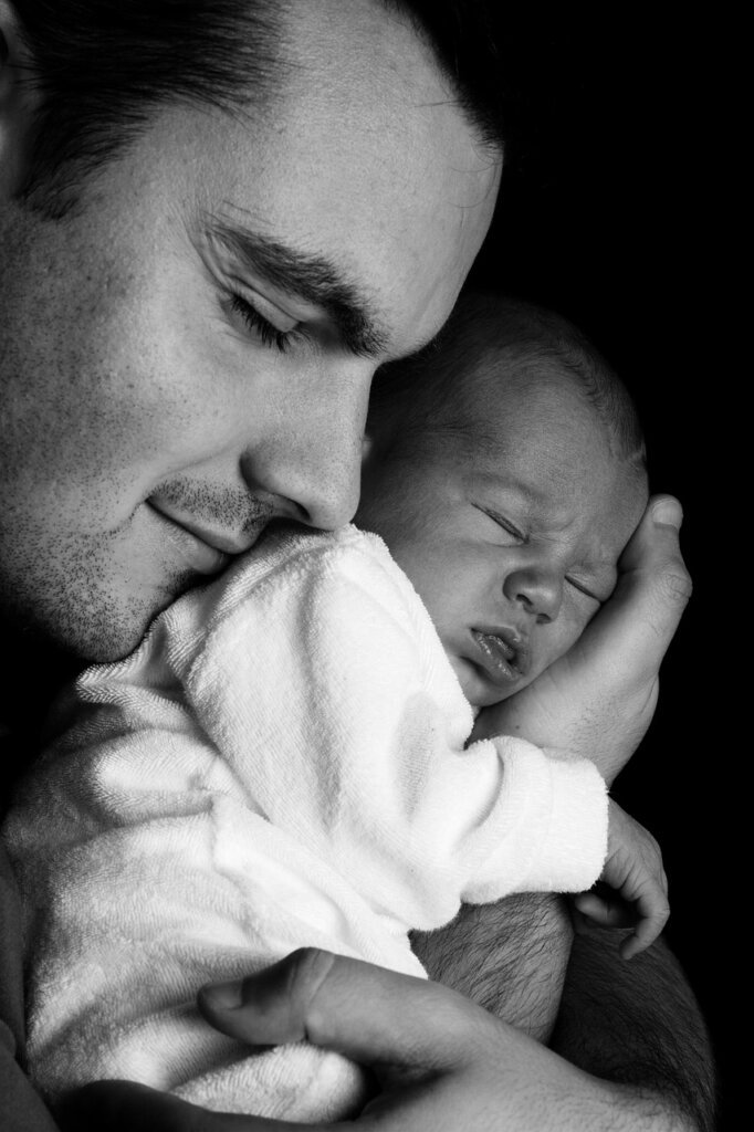 father holding baby while looking at clean bathroom, warm lighting