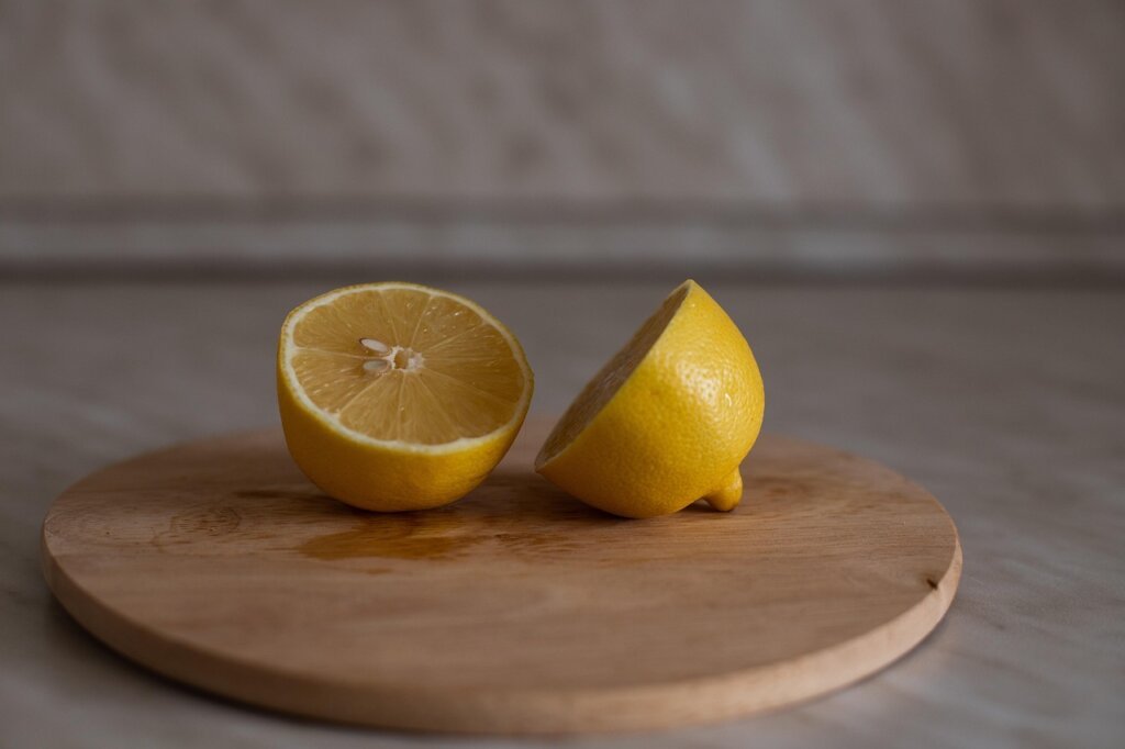 hand rubbing half lemon directly on plastic cutting board surface